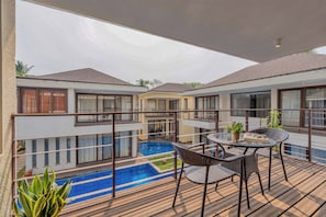 A balcony with a pool, outdoor seating, and a view of adjacent buildings. - Staymaster Casa Amaira 3BR Villa  (Vagator)