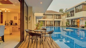 A modern hotel with a pool, dining area, and a second-story balcony. - Staymaster Casa Amaira 3BR Villa  (Vagator)