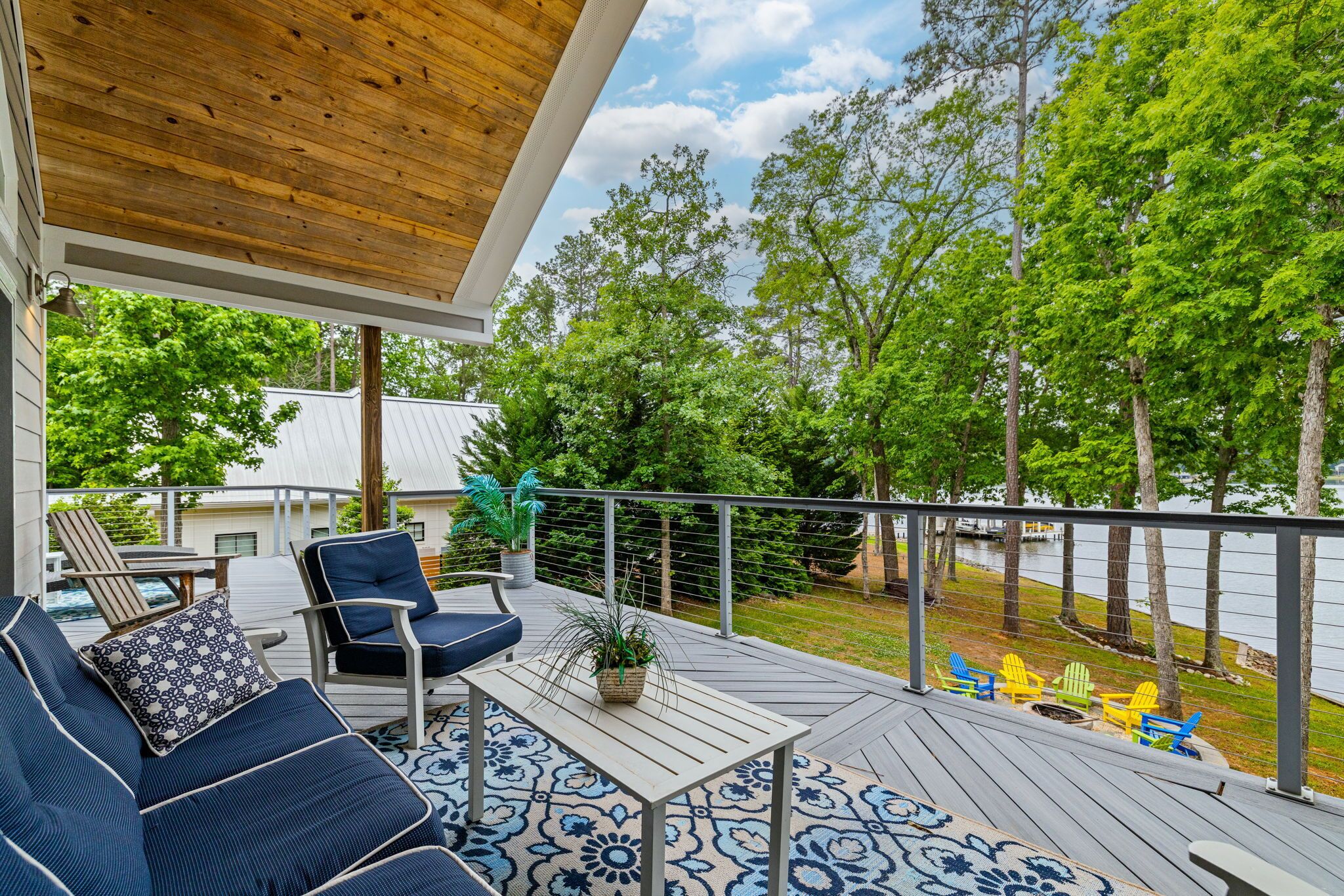 A covered deck with outdoor furniture, a view of a lake, and trees.