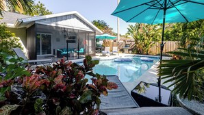 A backyard with a swimming pool, a covered patio, and a house with a glass enclosure. - Summer House - Oasis pool house in the heart of Sarasota (Sarasota)