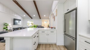 A modern kitchen with white cabinetry, a large island, and a stainless steel refrigerator. - Summer House - Oasis pool house in the heart of Sarasota (Sarasota)