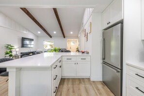 Eine moderne Küche mit weißen Schränken, einer großen Kochinsel und einem Edelstahl-Kühlschrank.