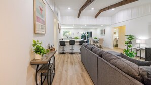 A spacious living area with a sofa, a wooden coffee table, and a kitchen in the background. - Summer House - Oasis pool house in the heart of Sarasota (Sarasota)