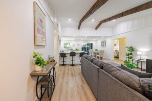 Ein geräumiger Wohnbereich mit einer Couch, einem Holztisch und einer Küche im Hintergrund.