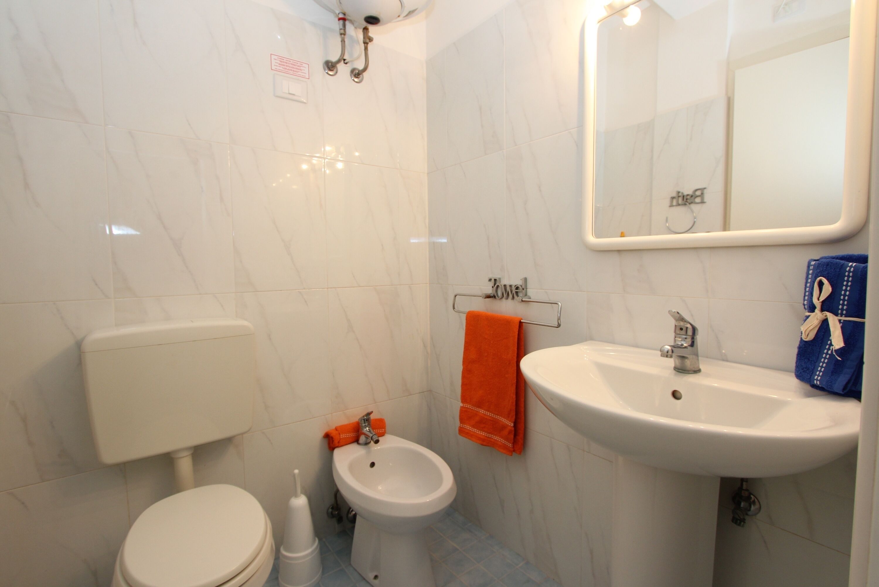 Ein Badezimmer mit Toilette, Bidet, Waschbecken und Spiegel.