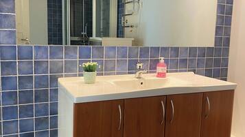 A bathroom with a wooden vanity, a mirror, and blue-tiled walls.