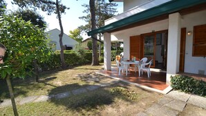 A covered patio with outdoor furniture, a stone pathway, and a well-maintained garden. - Cozy Two-level Retreat With Garden (San Michele al Tagliamento)