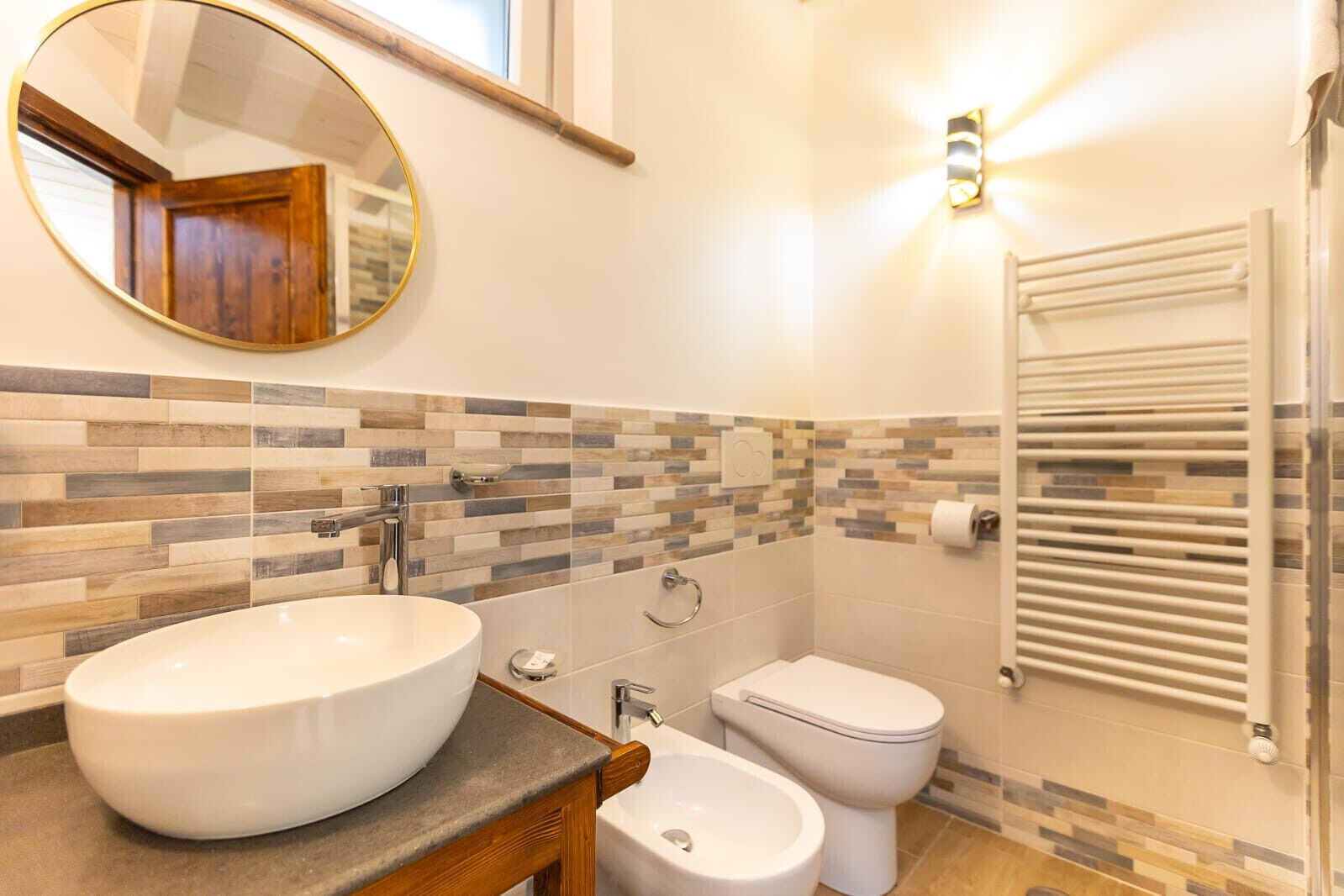A bathroom with a round sink, a toilet, and a bidet.