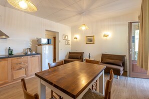 A compact kitchen with a wooden table, chairs, a microwave, and a refrigerator. - Le Vigne - Appartamento La Maremma (Bolsena)