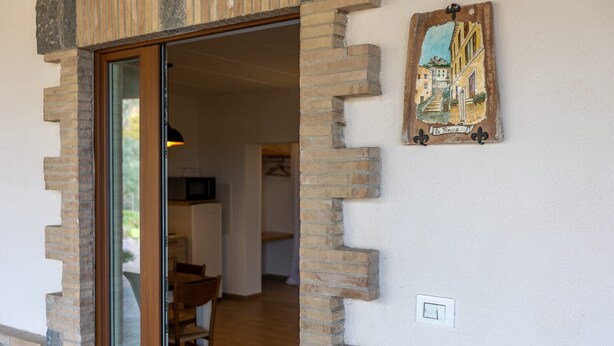 Une porte qui mène à une pièce dotée d’un plancher en bois, d’une chaise et d’une table.