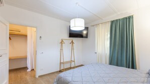 Une chambre à coucher comprenant un lit, une télévision, une armoire et un portant à vêtements.