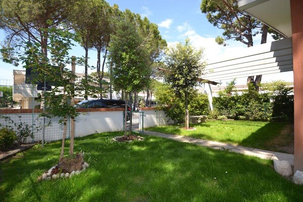 Una zona residenziale con un edificio bianco, un vialetto lastricato e diversi alberi.