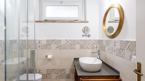 A bathroom with a glass shower enclosure, a toilet, a sink with a vessel basin, a vanity with a wooden cabinet, a gold-framed mirror, and patterned tiles on the walls. - Le Vigne - Appartamento Palazzo Chiavoni (Bolsena)