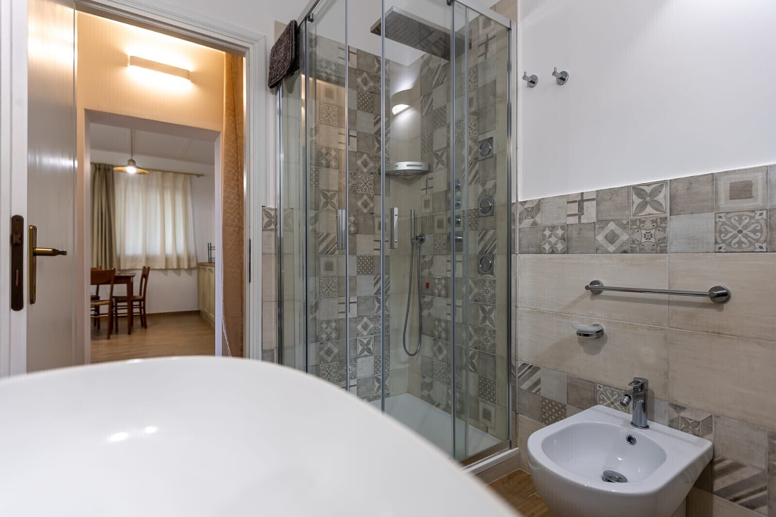 A bathroom with a glass shower enclosure, a bidet, and a sink.