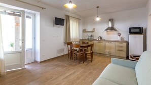 A compact living space with a dining area, kitchenette, and a sofa. - Le Vigne - Appartamento Palazzo Chiavoni (Bolsena)