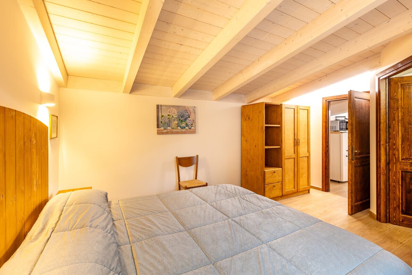 Une chambre à coucher avec un lit, une armoire en bois et une chaise.