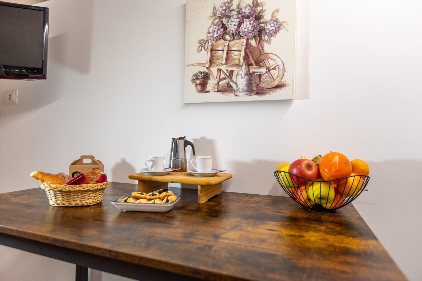 A breakfast setup with bread, pastries, coffee, and fruit on a wooden table.