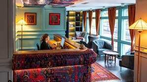 A lounge area with a patterned sofa, a small table, and a bookshelf. - Ginger Hotel (Tbilisi)