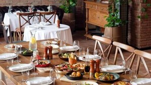 A restaurant with a long wooden table set for a meal, hanging pendant lights, and a brick wall in the background. - Ginger Hotel (Tbilisi)
