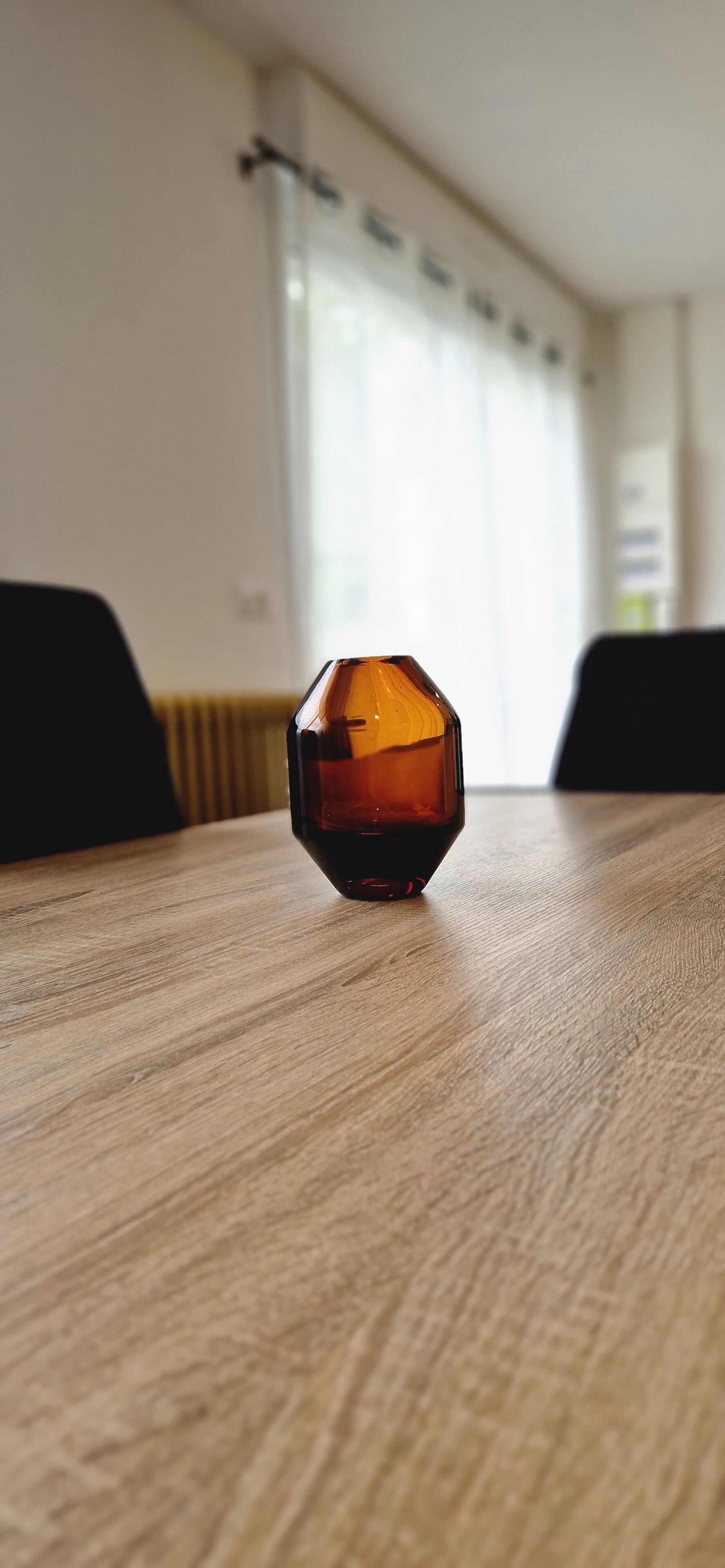 Un objeto de vidrio hexagonal sobre una mesa de madera en una habitación con ventana y radiador.