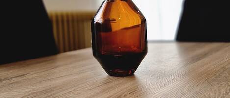 Un objeto de vidrio hexagonal sobre una mesa de madera en una habitación con ventana y radiador.
