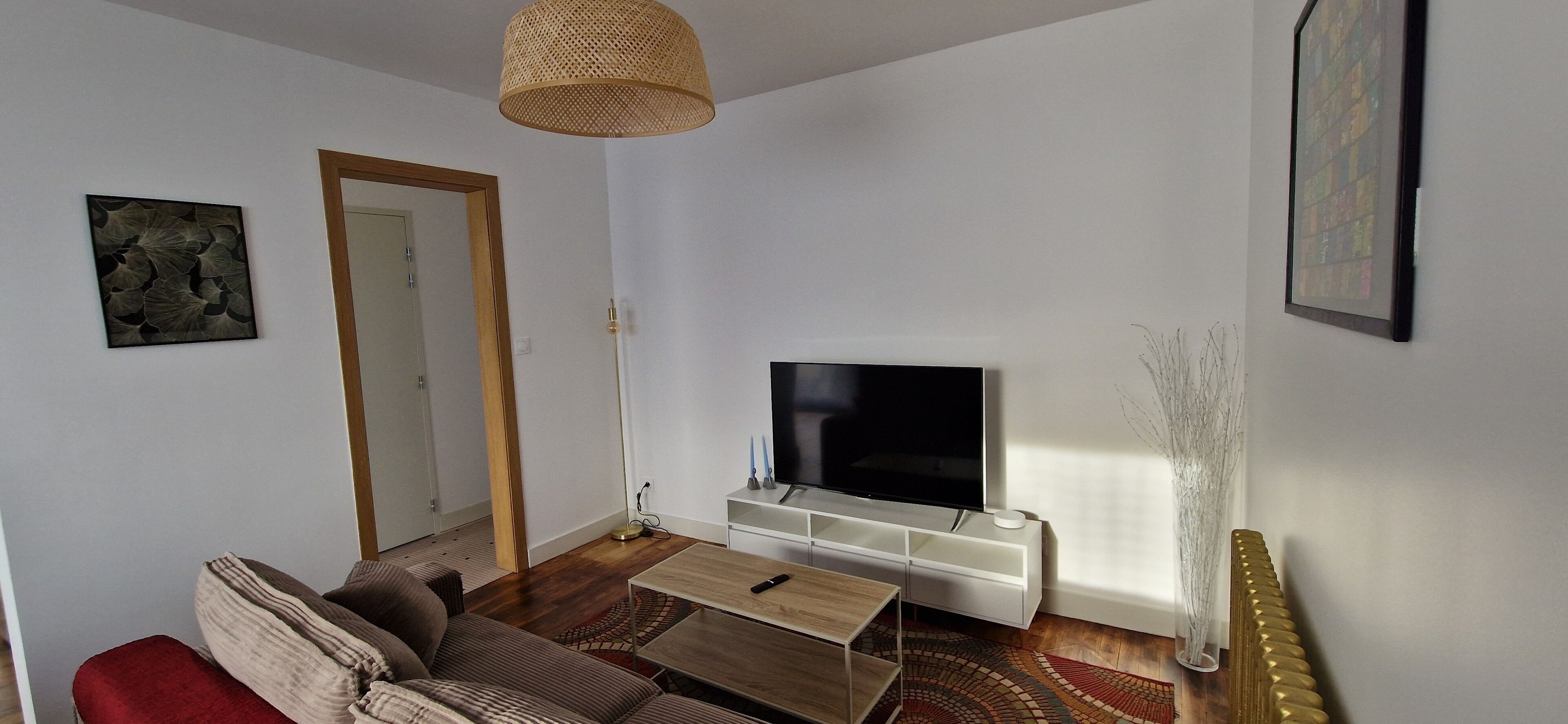 A living room with a flat-screen TV, a sofa, a coffee table, and a patterned rug.