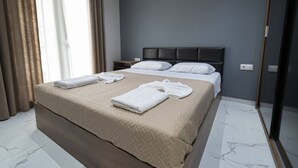 A modern hotel room with a large bed, a bedside table, and a wardrobe. - Central Cozy Home by Rentals Pro - Nea Moudania Halkidiki (Nea Moudania)