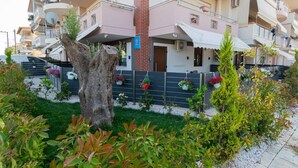 Un immeuble résidentiel à plusieurs étages, doté de balcons, d’un pilier en briques et de jardinières suspendues.