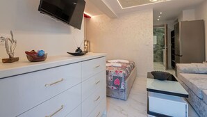 Une chambre moderne équipée d’une télévision, d’un lit, d’une commode et d’une petite table.