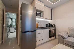 Eine moderne Küche mit eingebauter Mikrowelle, einem Edelstahlkühlschrank und einem Essbereich mit grauem Sofa.