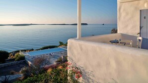 Blick auf das Meer von einer überdachten Außenterrasse mit Pool, einer Pergola und einem Tisch mit Stühlen.