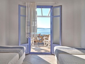 A room with two beds, a view of the sea, and a table with chairs outside. - Seafront Villa Thea -island Living- (Paros)