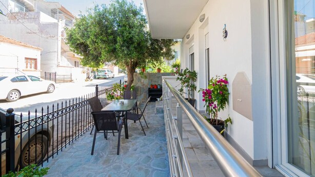 A balcony with outdoor seating, a tree, and potted plants. - Sweet Home by RentalsPro - Nea Moudania (Nea Moudania)