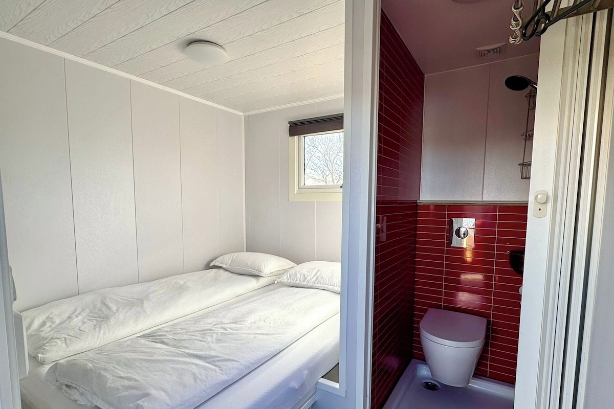 A single bed with white bedding in a room with white walls and a window.
