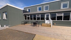 A two-story building with a deck, a door, and windows. - Hvítá Trucks by Ourhotels (Borgarbyggd)