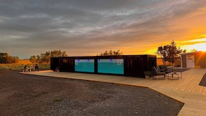 Un espace extérieur moderne, aménagé avec une terrasse en bois et doté de deux grands écrans.