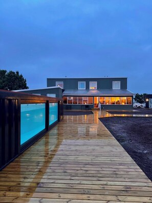 Ein modernes Gebäude mit einer Holterrasse, die zu einem gläsernen Bereich führt.