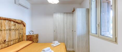 A bedroom with a bed, a wooden headboard, a wardrobe, and a window.
