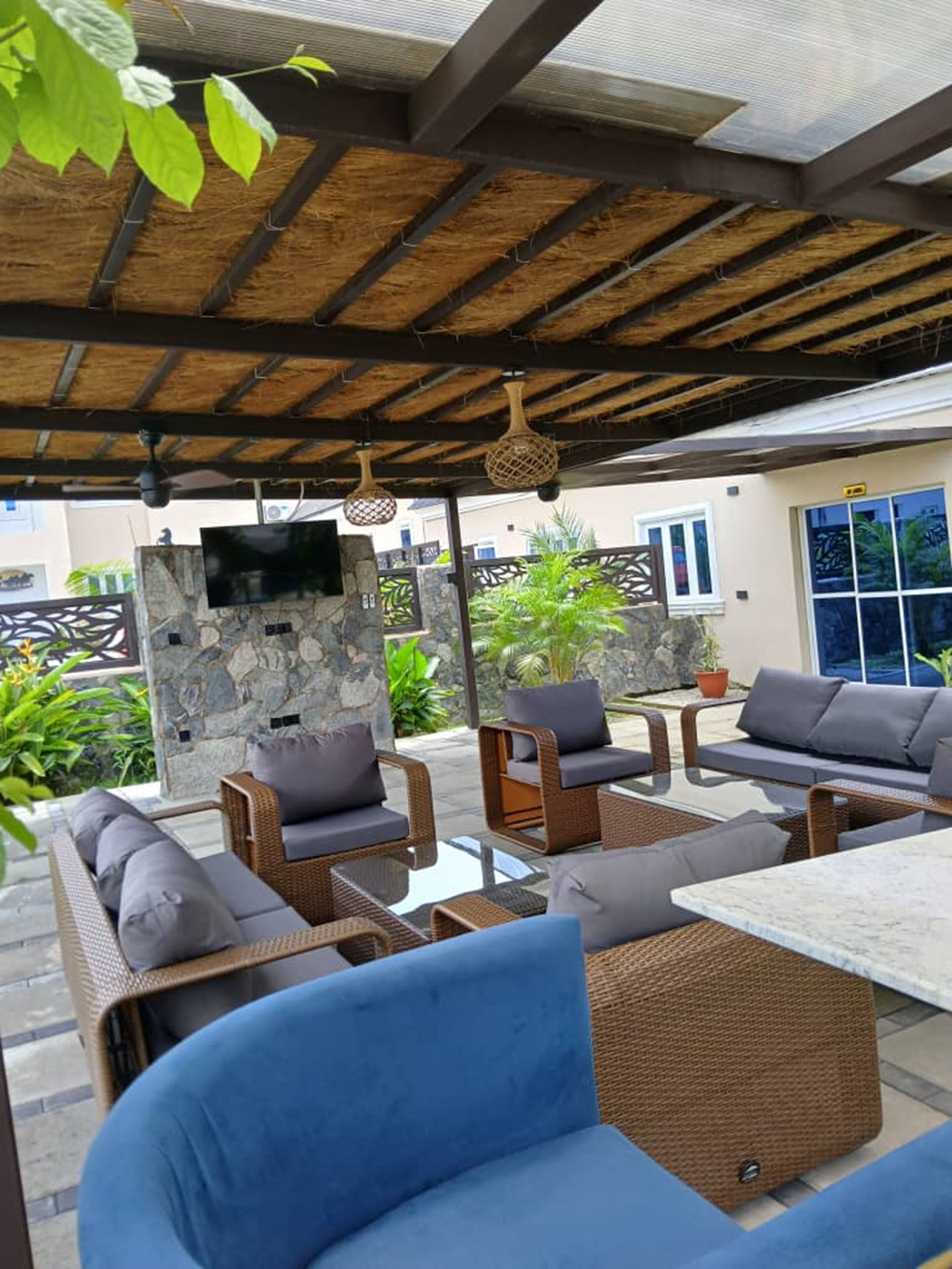 An outdoor patio area with wicker furniture, a stone wall, and a TV mounted on the wall.