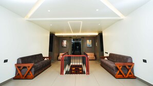 A modern interior with a central staircase, two sofas, and a geometric ceiling design. - Sukoon By Spynora (Vythiri)