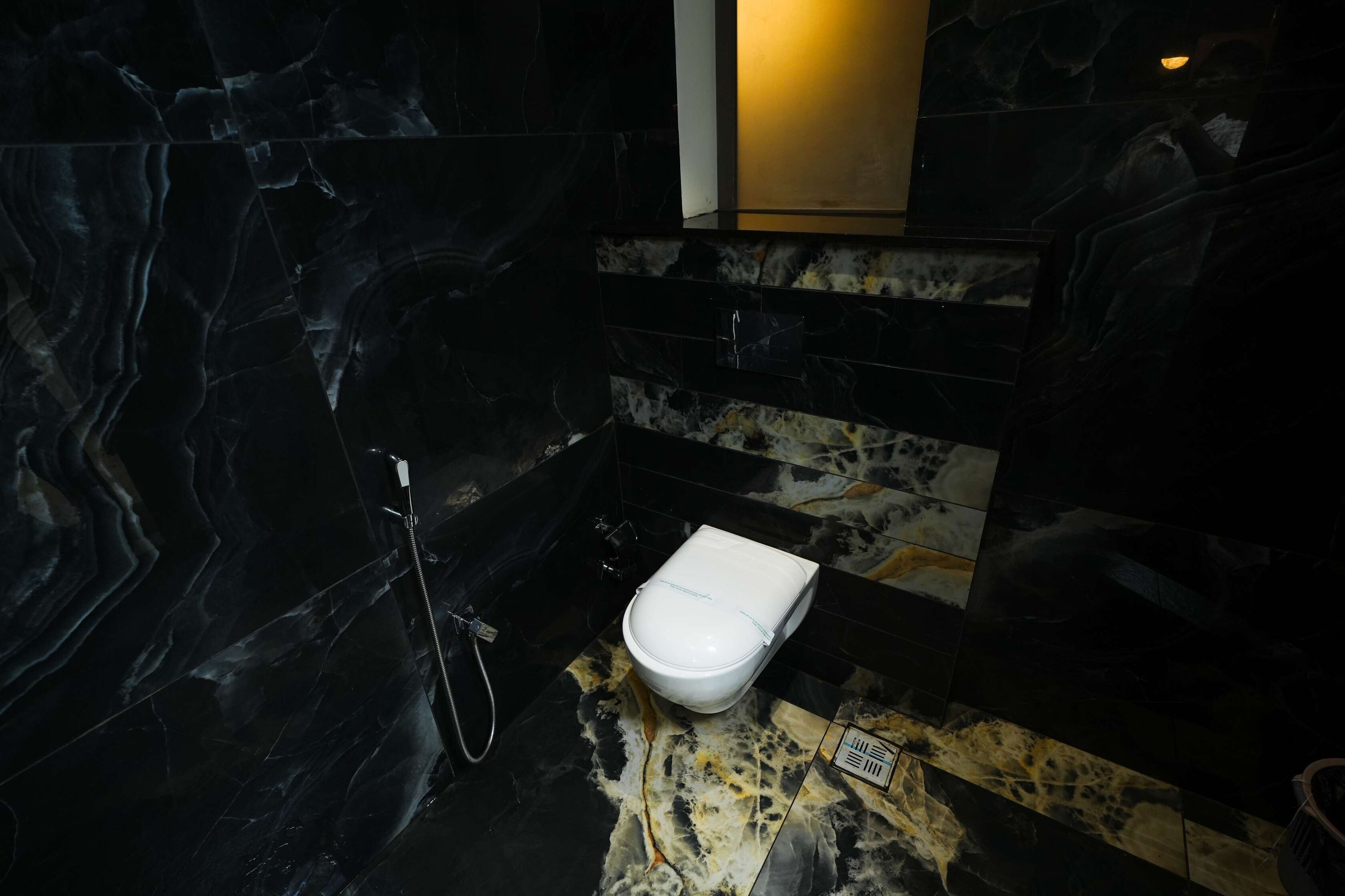 Une salle de bain avec des toilettes blanches, une douche et un mur en marbre.
