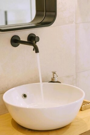 Ein weißes Keramikbecken mit einem schwarzen Wasserhahn an einer gefliesten Wand.
