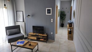 Ein modernes Wohnzimmer mit grauem Sofa, Couchtisch, Fernseher und Kamin.