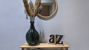 Ein hölzerner Konsolentisch mit einer Vase mit getrocknetem Pampasgras, einem Spiegel und einigen Büchern.