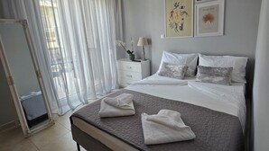 Ein modernes Schlafzimmer mit einem großen Bett, einem Nachttisch mit Lampe, einem Spiegel und Kunstwerken an der Wand.