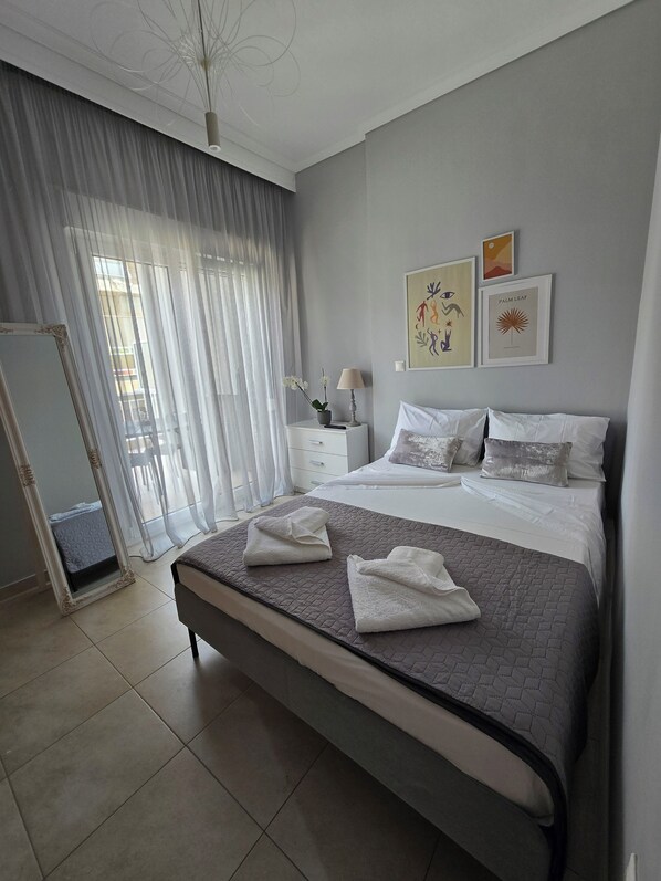 A modern bedroom with a large bed, a bedside table with a lamp, a mirror, and artwork on the wall.