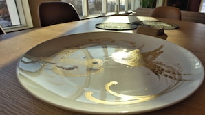 Una mesa de comedor con un plato decorativo con diseños de pájaros.