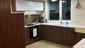 Una cocina moderna con armarios de madera, horno integrado, fregadero y ventana.