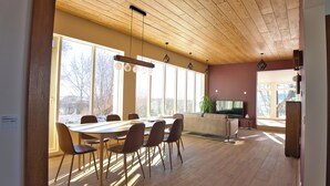 Un comedor moderno con techo de madera, ventanas amplias y una televisión de pantalla plana.