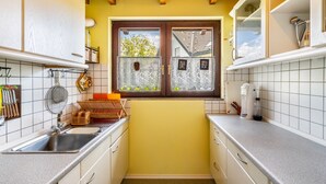 Eine kleine Küche mit Fenster, Spüle und einer Kaffeemaschine.
